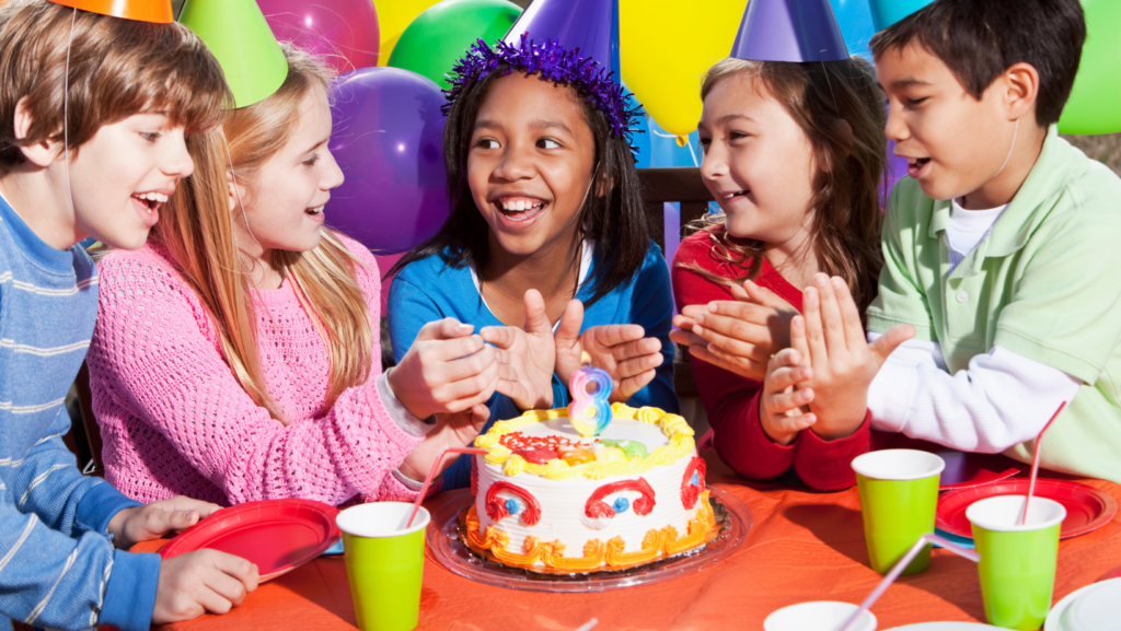Three kids sitting around a birthday cake at a home birthday party.