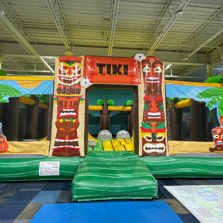 Colorful tiki themed inflatable obstacle course in private party gym.